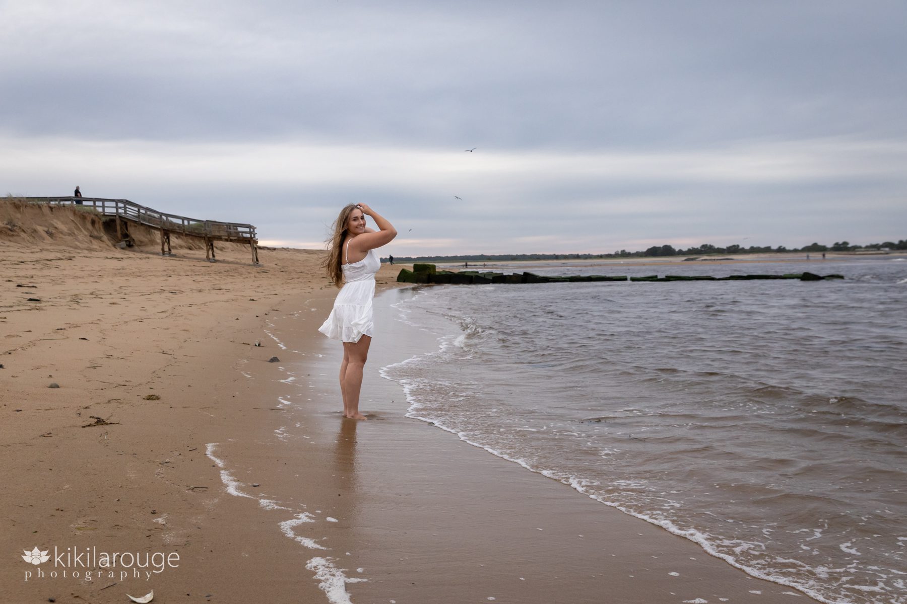 Triton Senior Portrait Girl in white dress looking back at beach