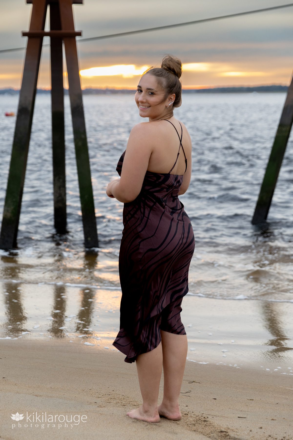 Girl in brown dress with hair blowing at Plum Island Beach at sunset looking over shoulder