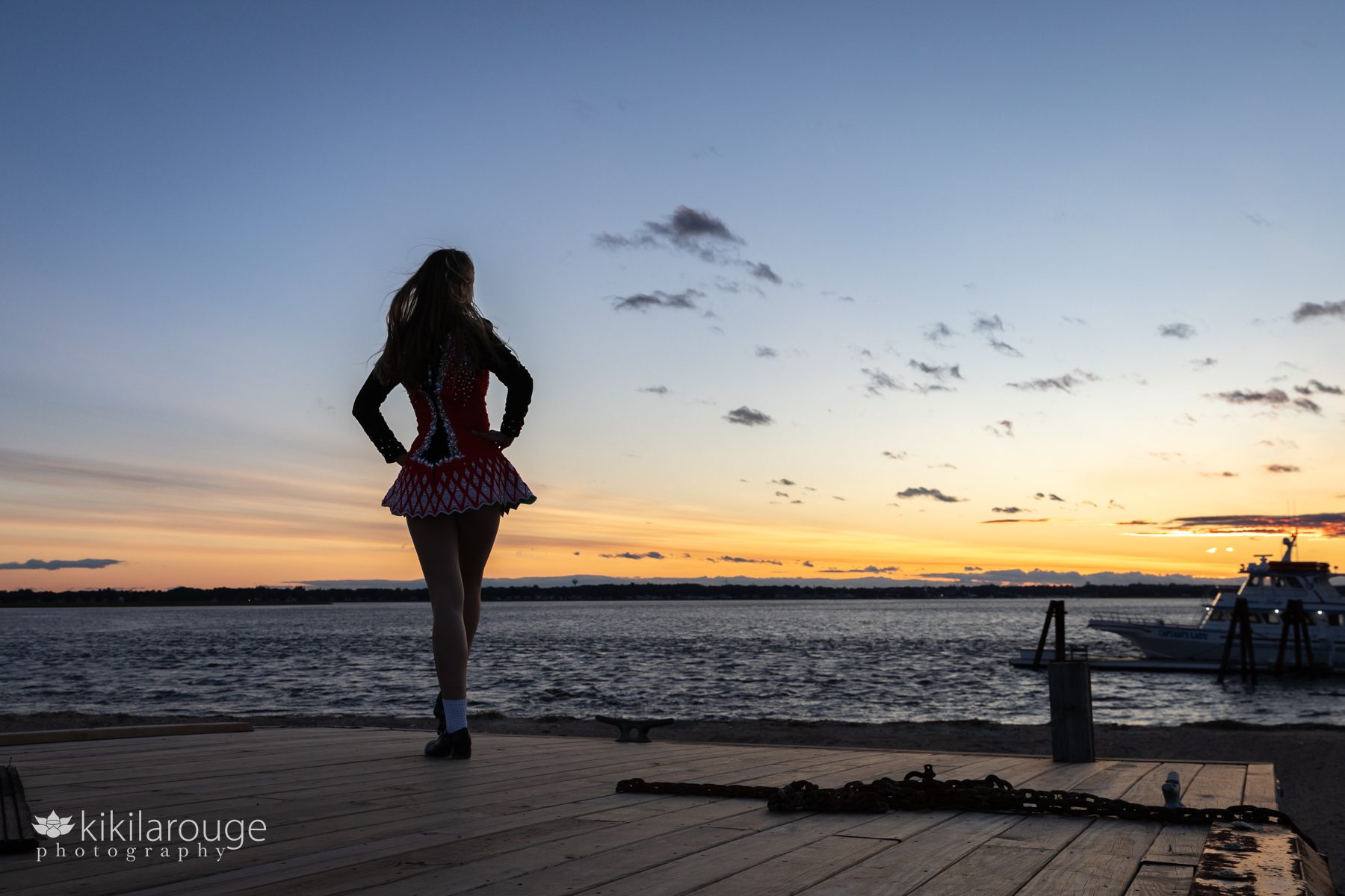 Silhouette of girl with long hair looking at sunset dressed in Irish Step Dancing outfit