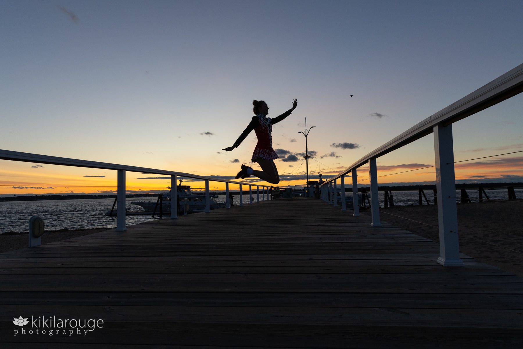 Teen girl in Irish Step Dancer outfit jumping in silhouette with feet behind on the plum Island pier