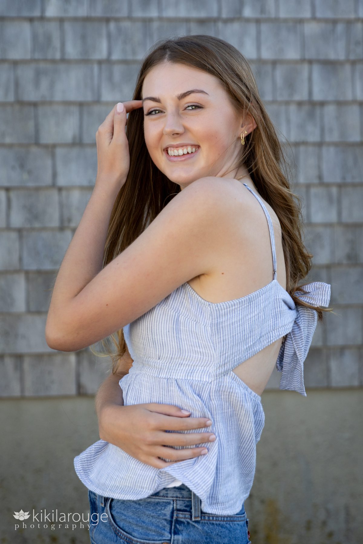 Smiling teen girl with hand in hair and on waist and a bow in back tops