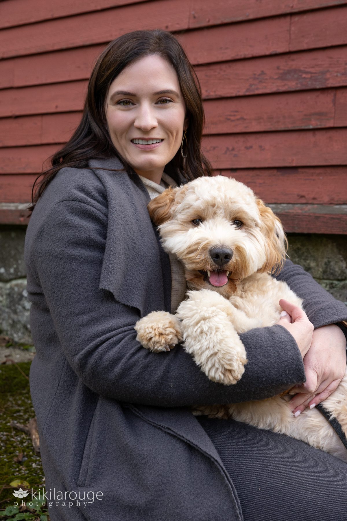Woman snuggling with labradoodle pup looking at camera
