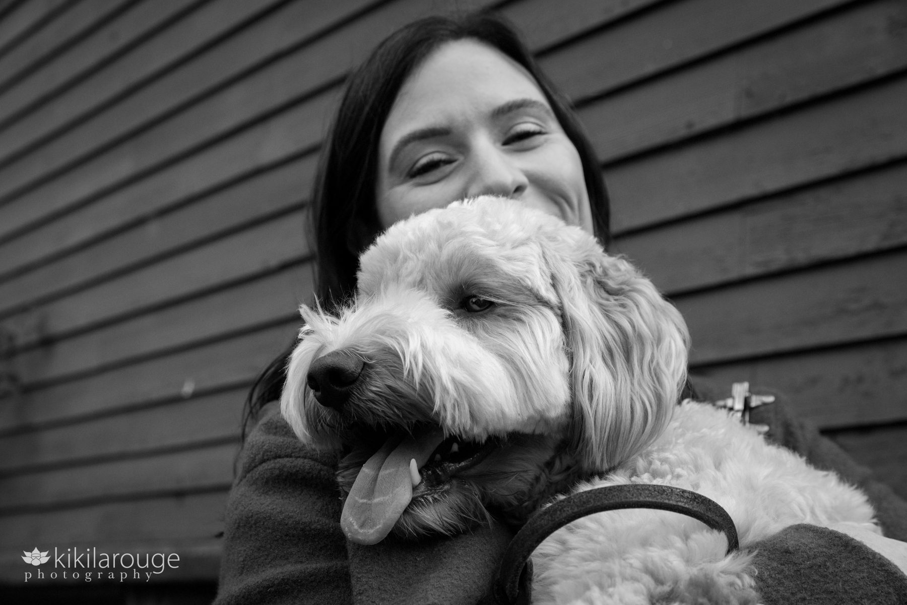 Woman snuggling with labradoodle pup looking at camera and laughing