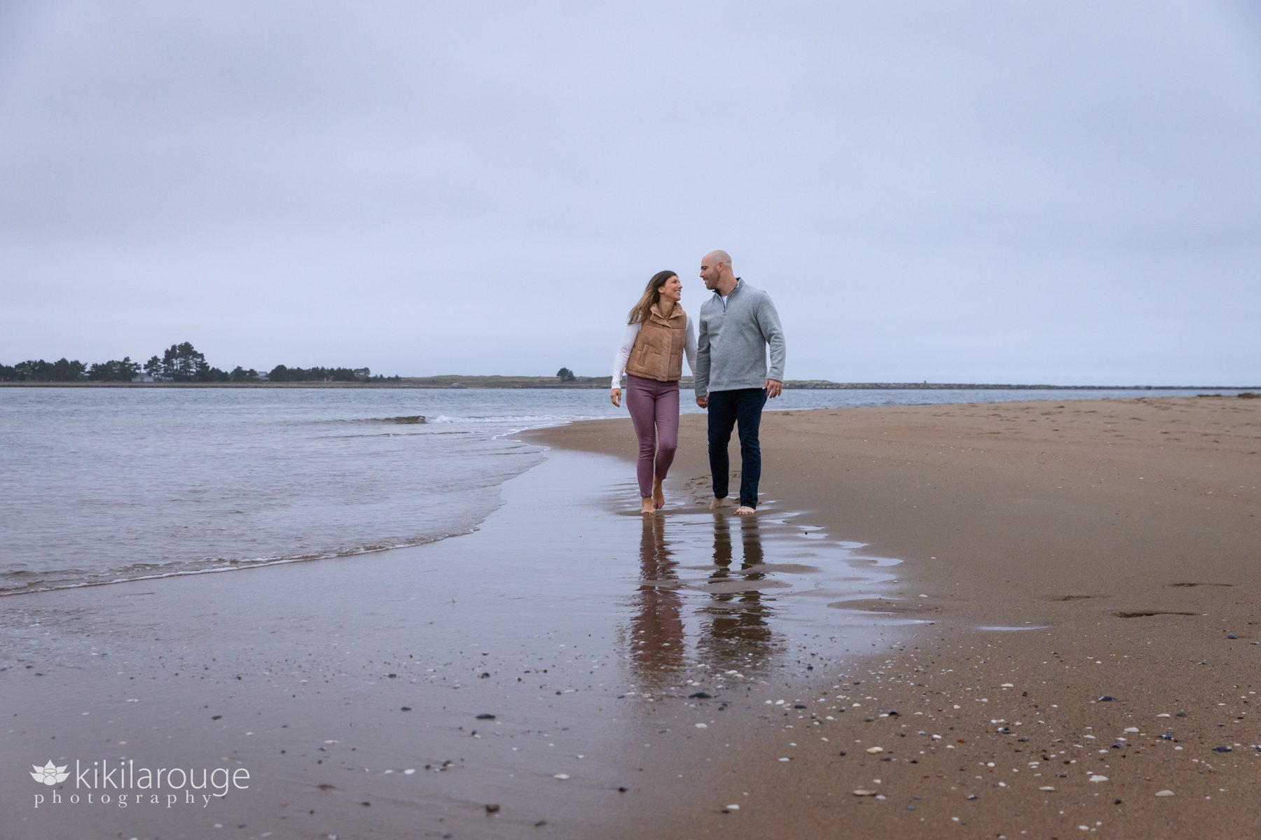 Couple walking along the Plum Island shoreline in the fall on an overcast day