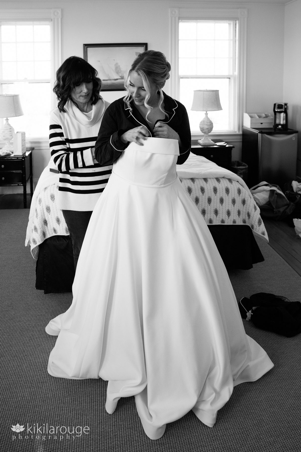 Mom in striped sweater helping her daughter out of PJs and into a bridal gown