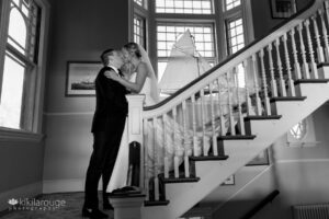 Wedding couple on stairs with long shadows and small sailboat replica in background
