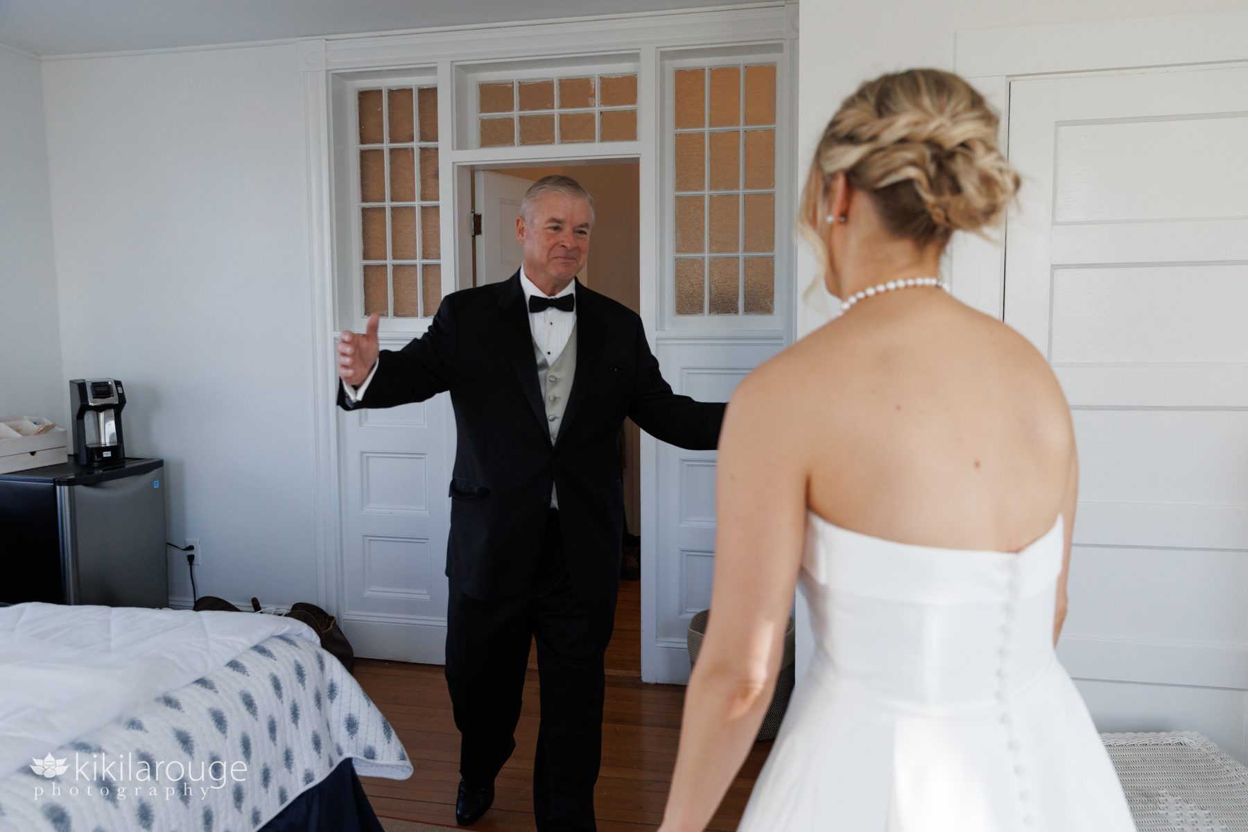First look with the father of the bride coming in room smiling at bride
