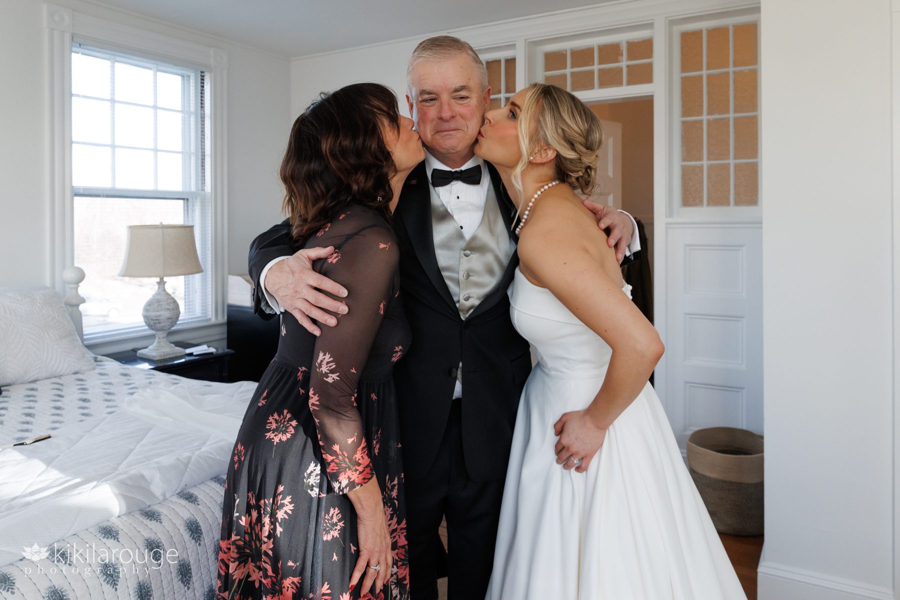 Bride and her Mom kissing Dad on wedding day