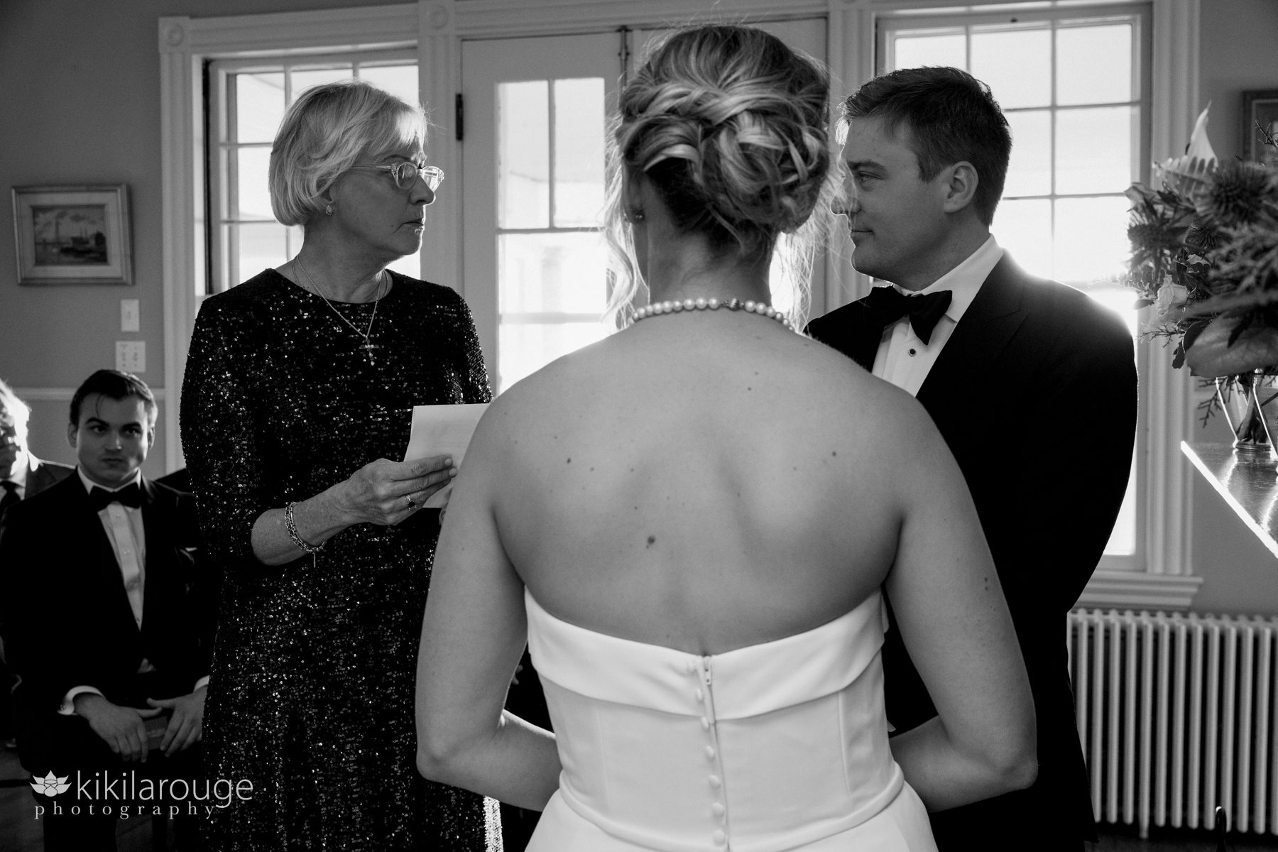 Back of bride with officiant looking at groom repeating vows on wedding day at Gloucester yacht club