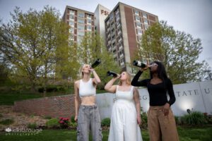 Three young woman swilling champagne from bottles at FSU celebrating graduating