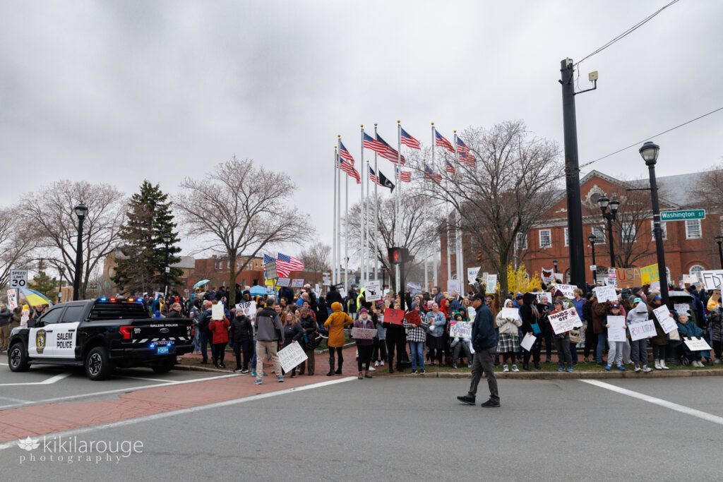 Group of protesters in Salem MA with USA flags on posts in background