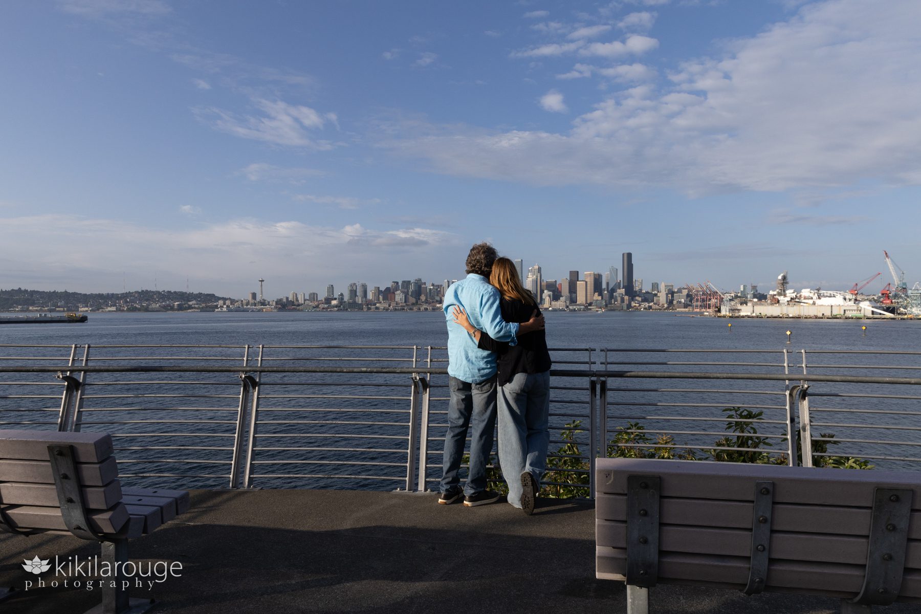 Couple embracing on platform looking out on the Seattle skyline from West Seattle