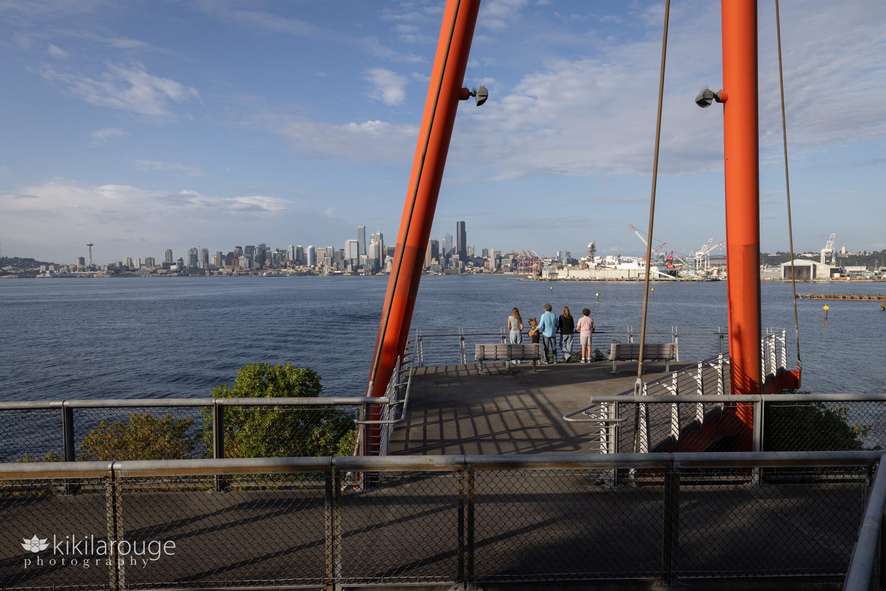 Family of four and their dog leaning on railing looking out on sweeping Seattle Skyline from West Seattle