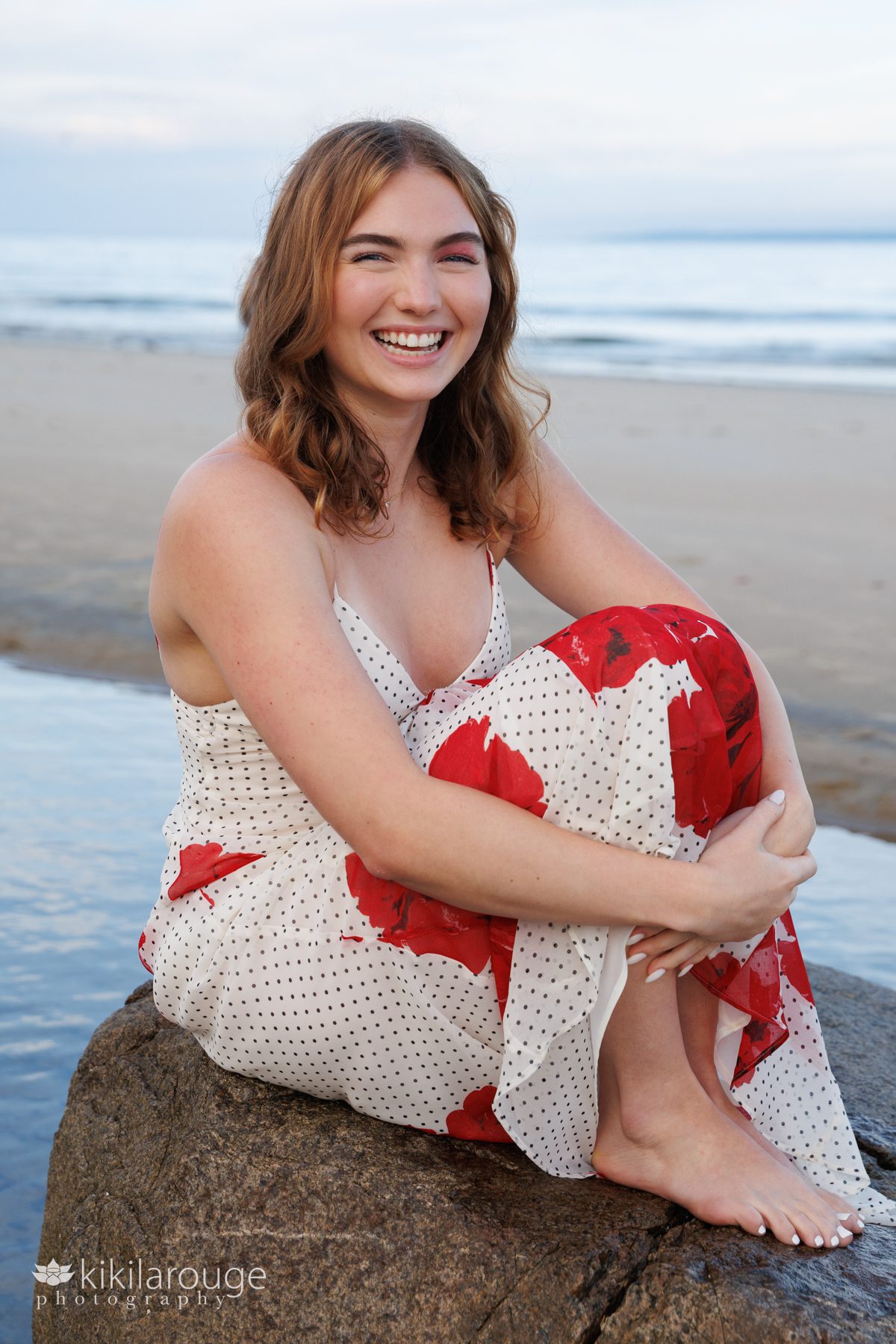 Girl walking sitting on a rock in a tidepool in long floral dress with black polka dots