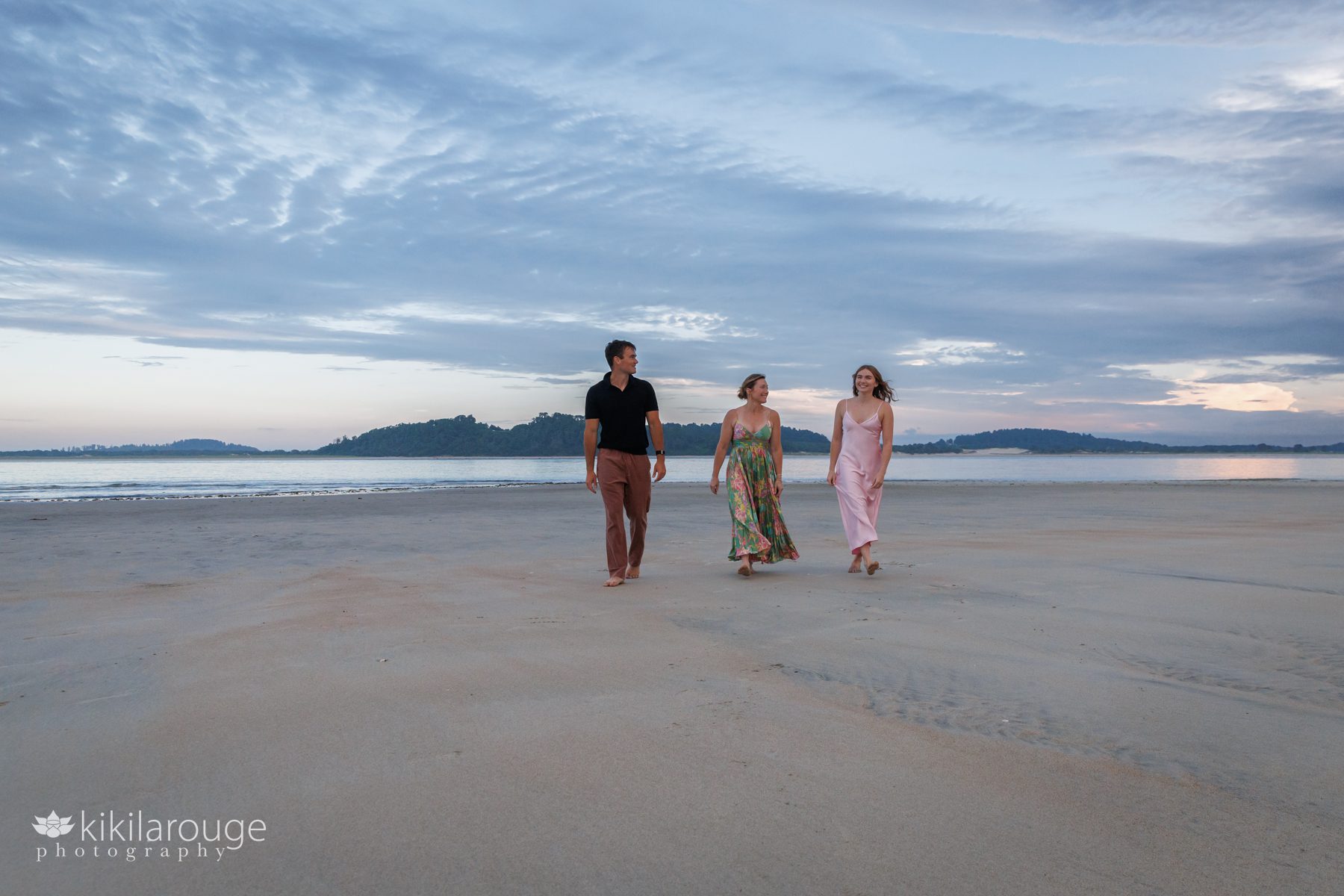Mom with her two kids walking on open beach talking and laughing together