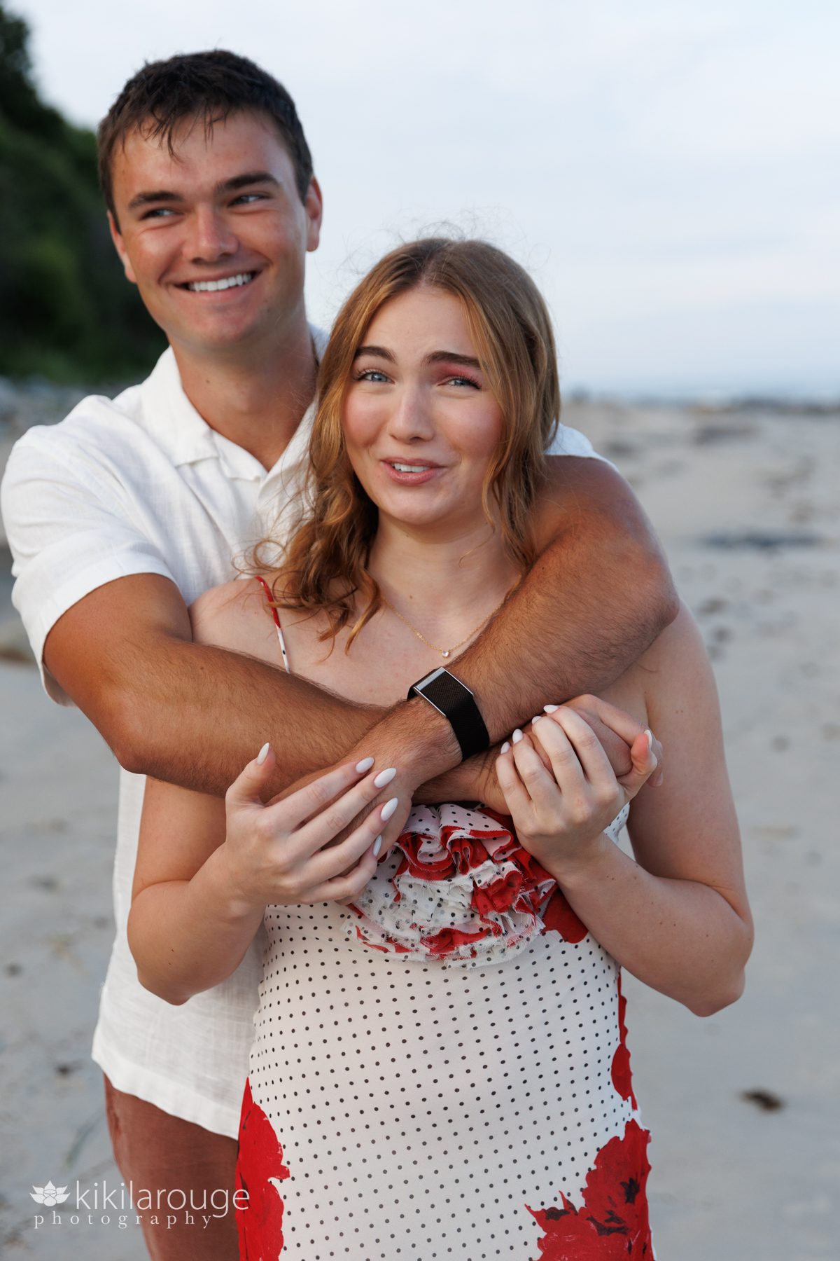 Brother and sister hugging and laughing at awkward pose at Sandy Point beach