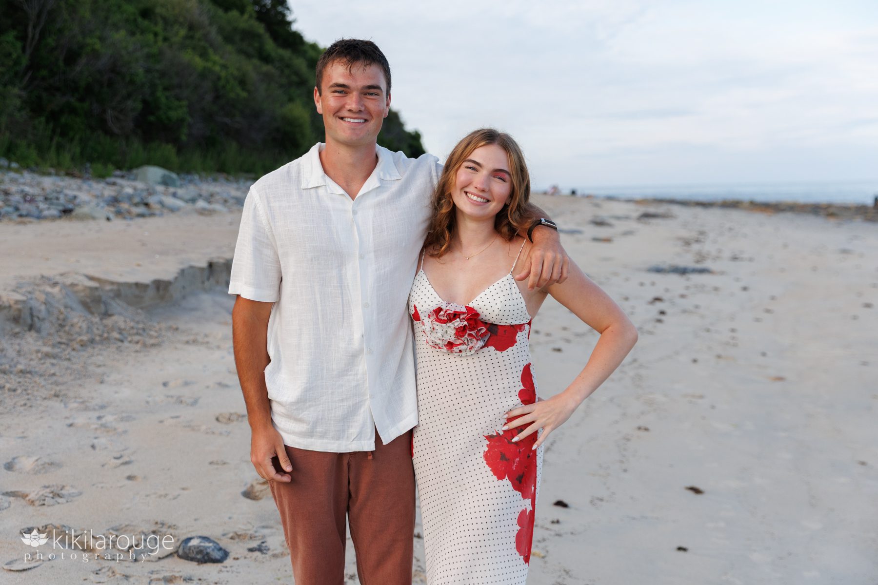 Brother and sister smiling together on Long Beach with green and ocean in backdrop