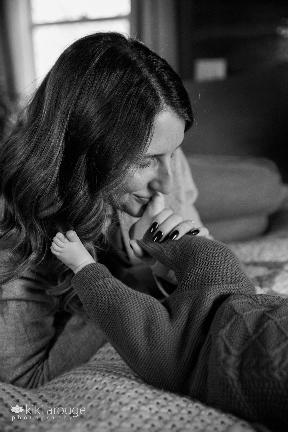 Mom with eyes closes kissing her two month old baby's sweet little toes