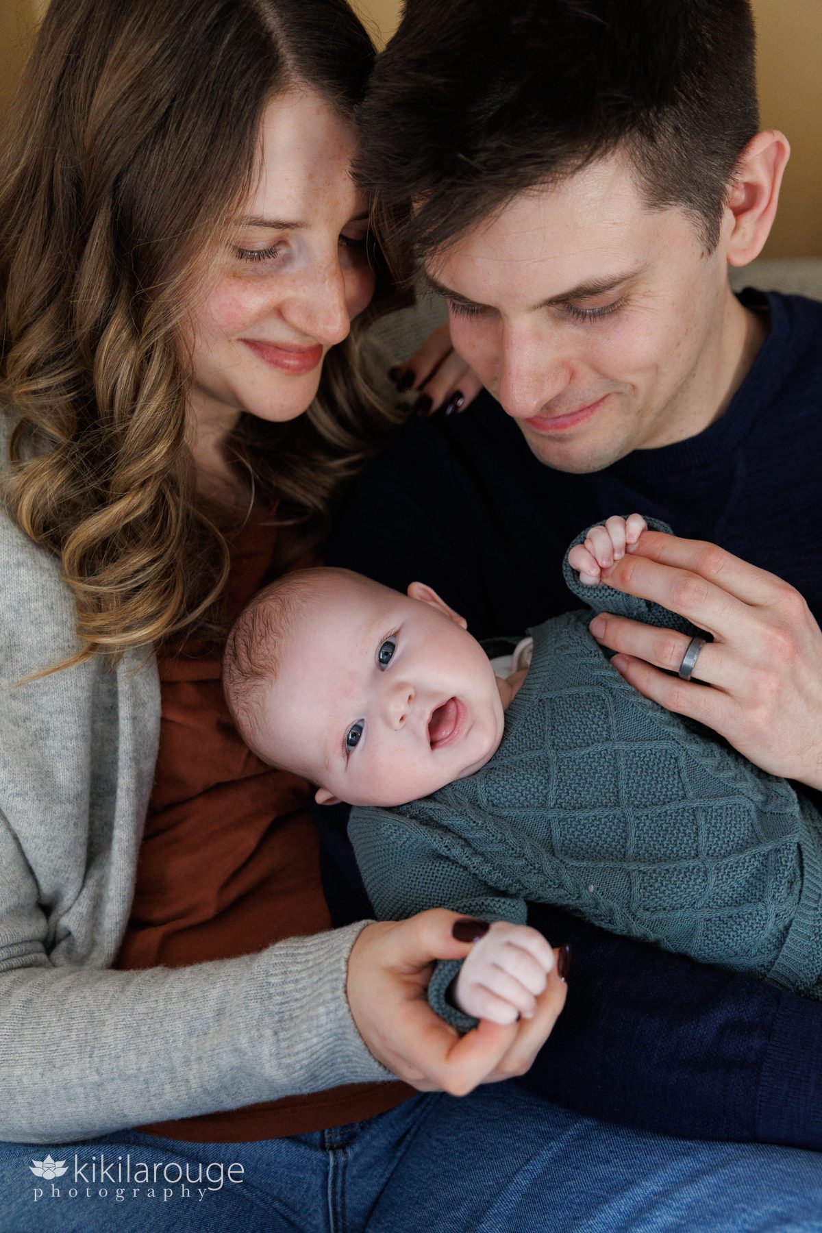 Mom and Dad smiling looking down on two month old baby in their arms
