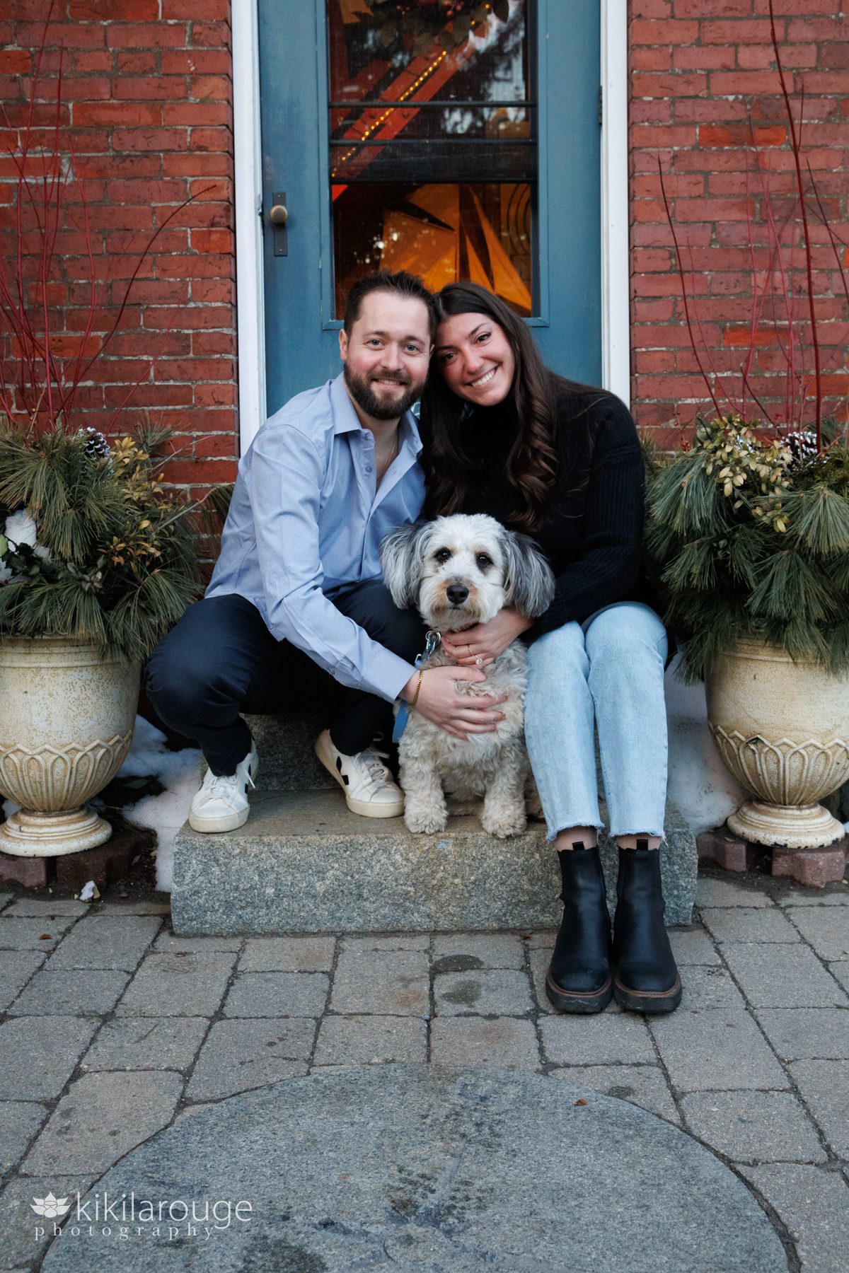 Cute couple sitting on steps of lighthouse with their dog
