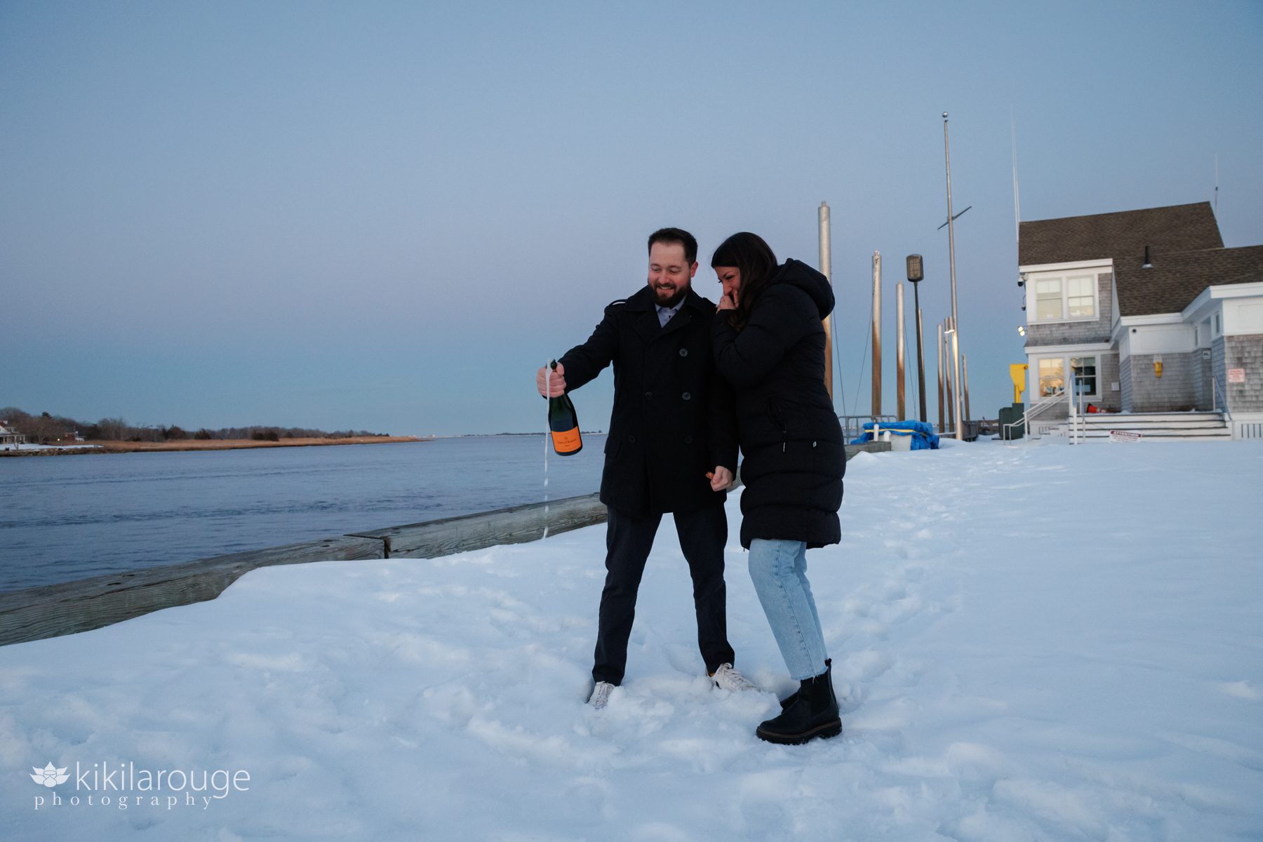 Couple popping Veuve champagne in the snow along the NBPT waterfront with Plum Island in background