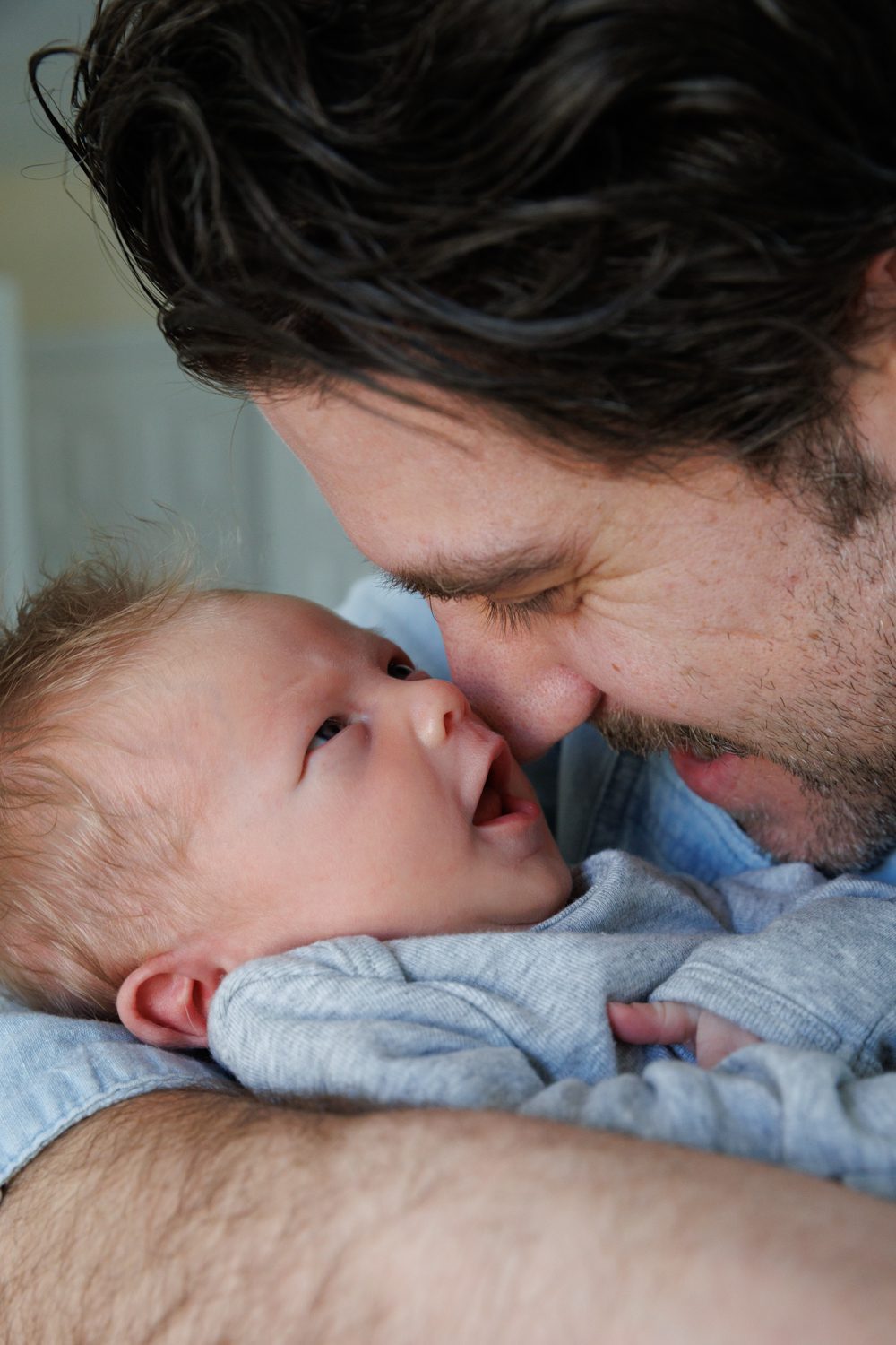 Close up of Dad's face nestled into his newborn who is also looking up with open mouth