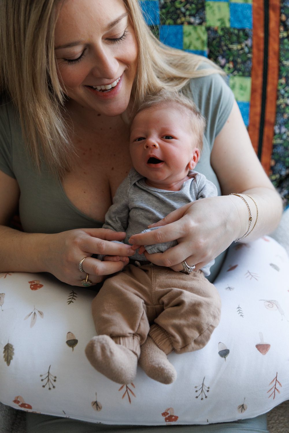 Mom smiling down on newborn son in between weddings with mushroom bobbie