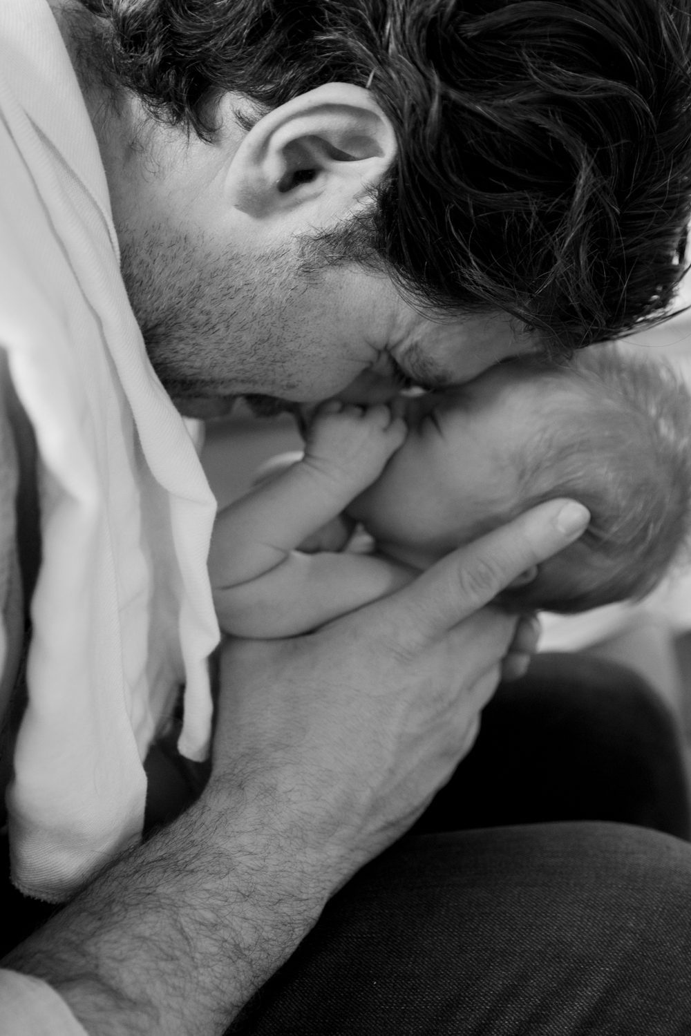 Dad and newborn baby with faces nestled together in cute embrace
