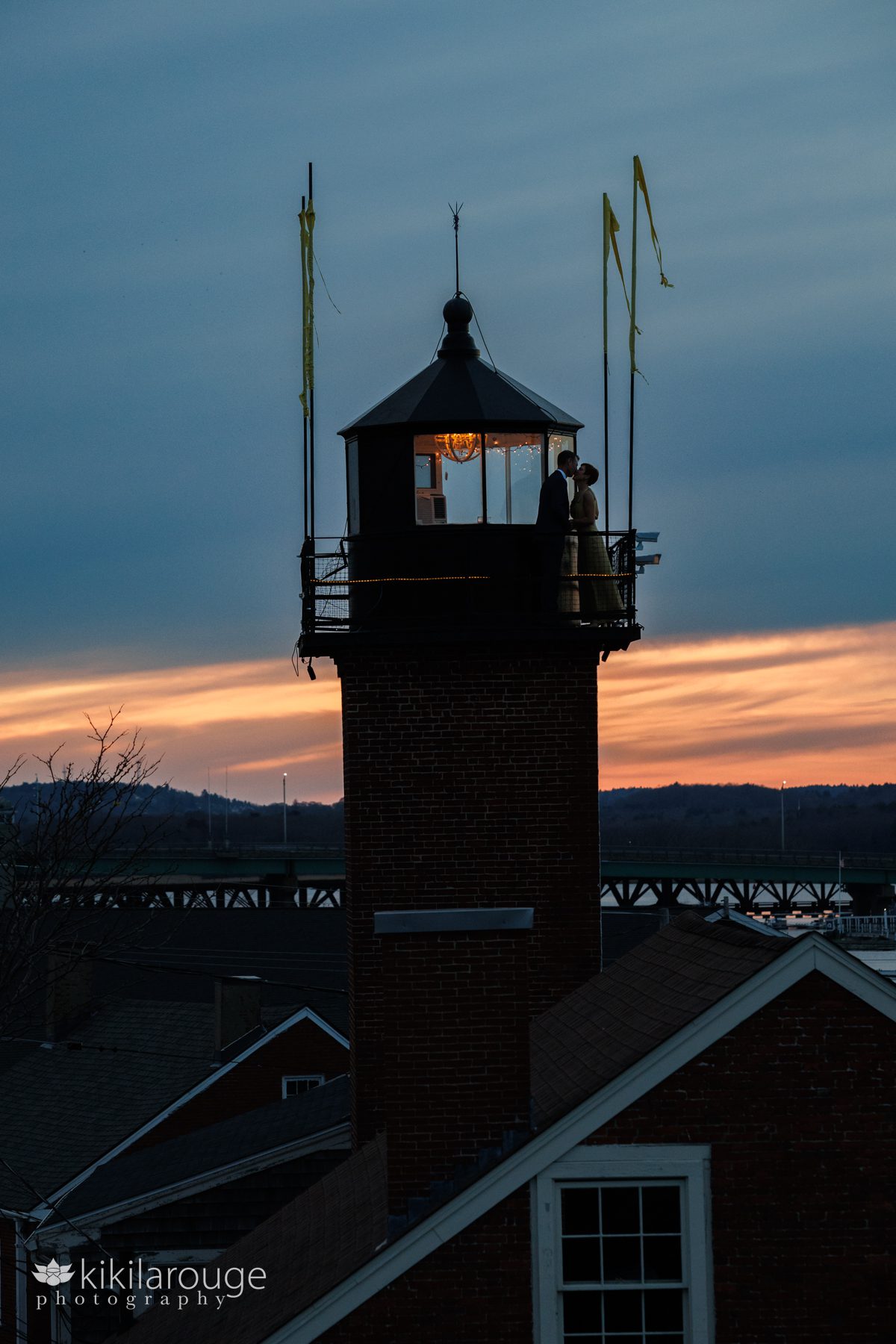 Silhouette of a couple kissing atop the Newburyport Lighthouse with dramatic fiery sunset
