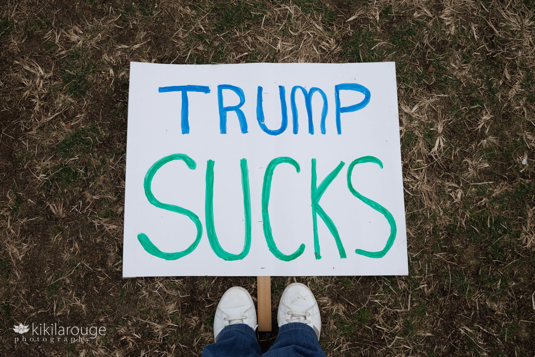 Standing over a TRUMP SUCKS sign at the end of the No Kings Boston Rally
