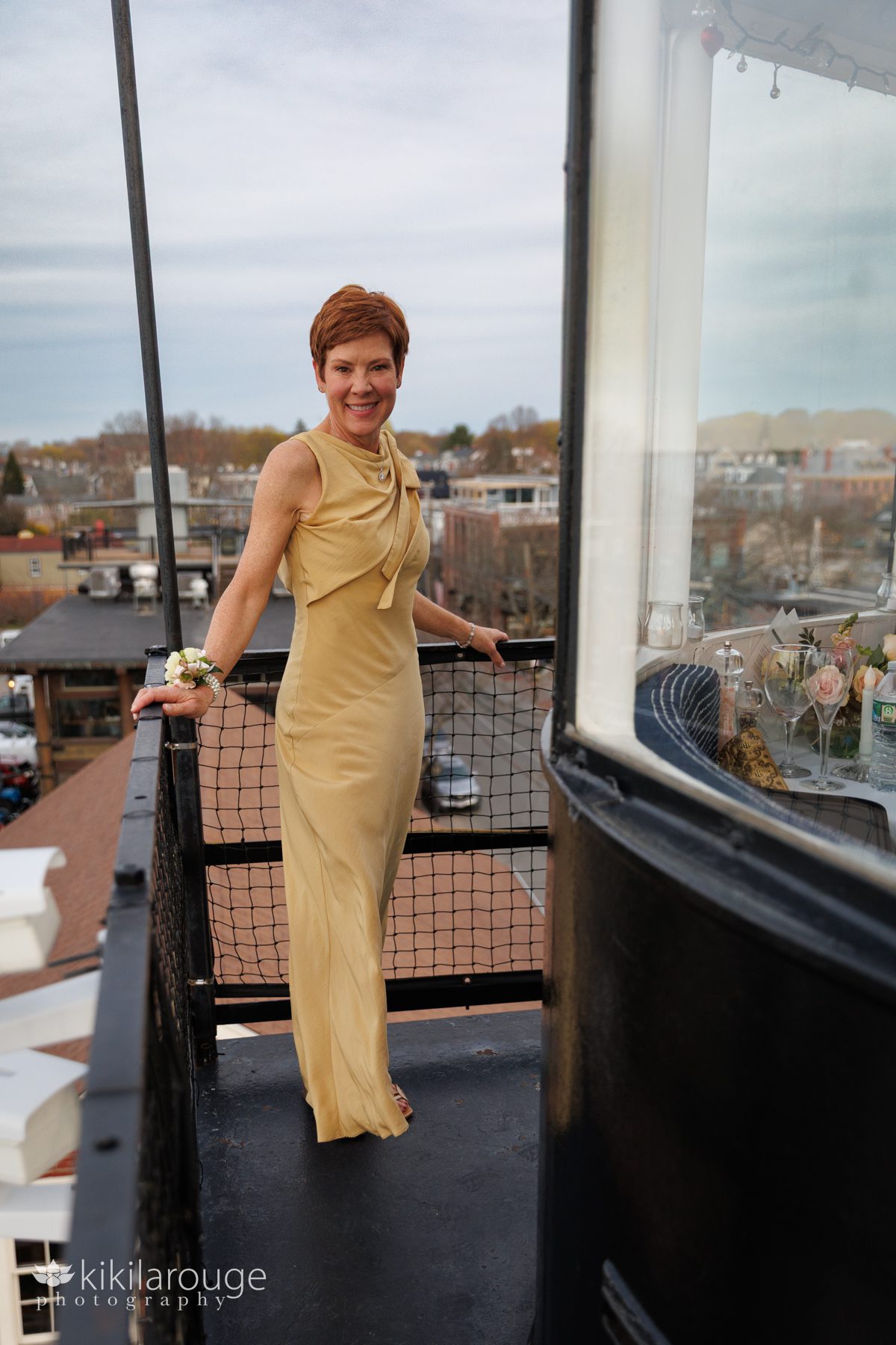 Woman atop the Newburyport lighthouse in gorgeous long golden dress with wedding corsage and city in the backdrop below