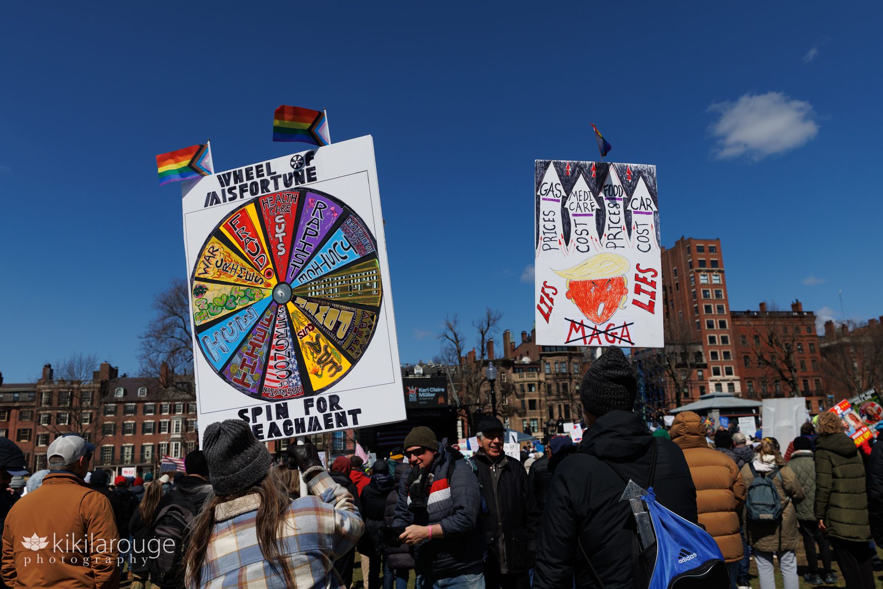 Wheel of Misfortune and Maga Lies hand made colorful signs as seen on the Boston Common at the No Kings Protest