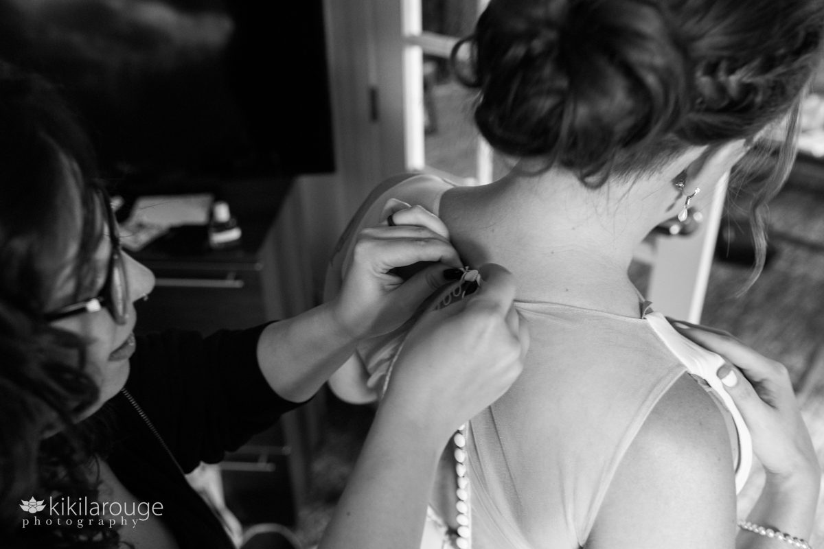 Woman buttoning up the back of a bridal gown 