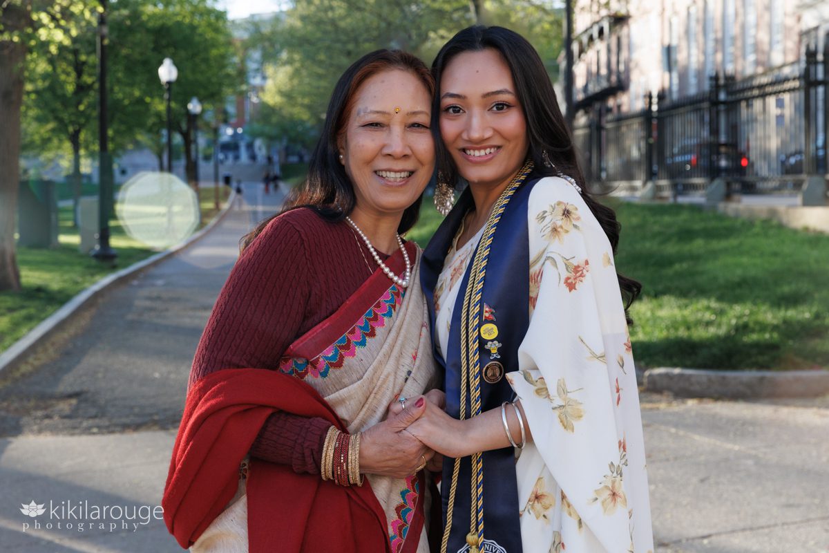 Nepali Mom and daughter in saris holding hands smiling at daughter's graduation celebration on Boston Common