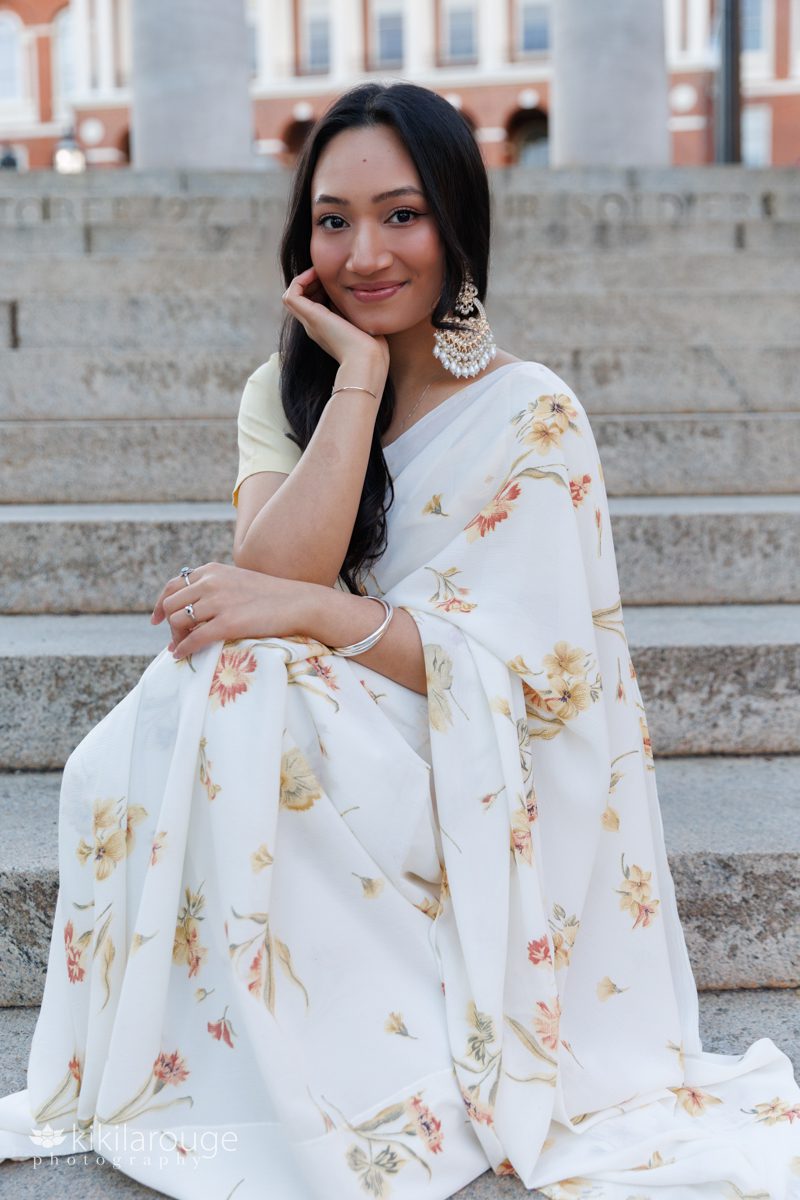 Beautiful Nepali woman in light pale yellow floral sari sitting on the cement steps in front of the MA State House in Boston