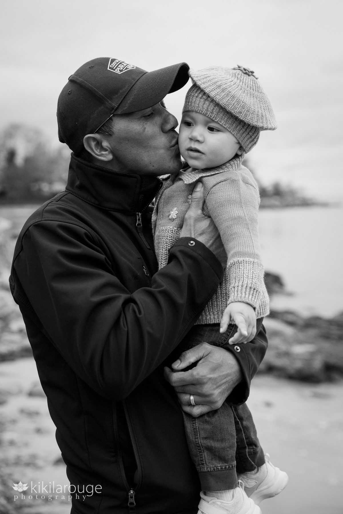 Cute Nepali Dad holding his toddler daughter at the beach giving her a kiss on the cheek