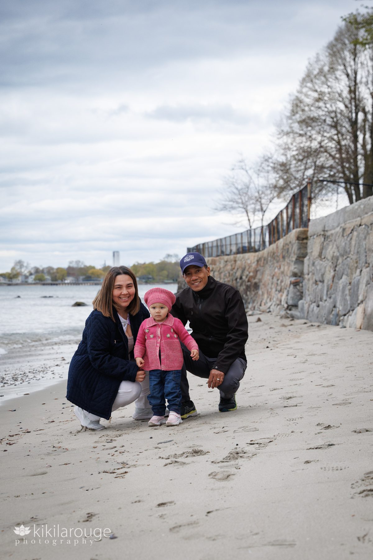 Couple on bean with their toddler daughter dressed in pink and denim