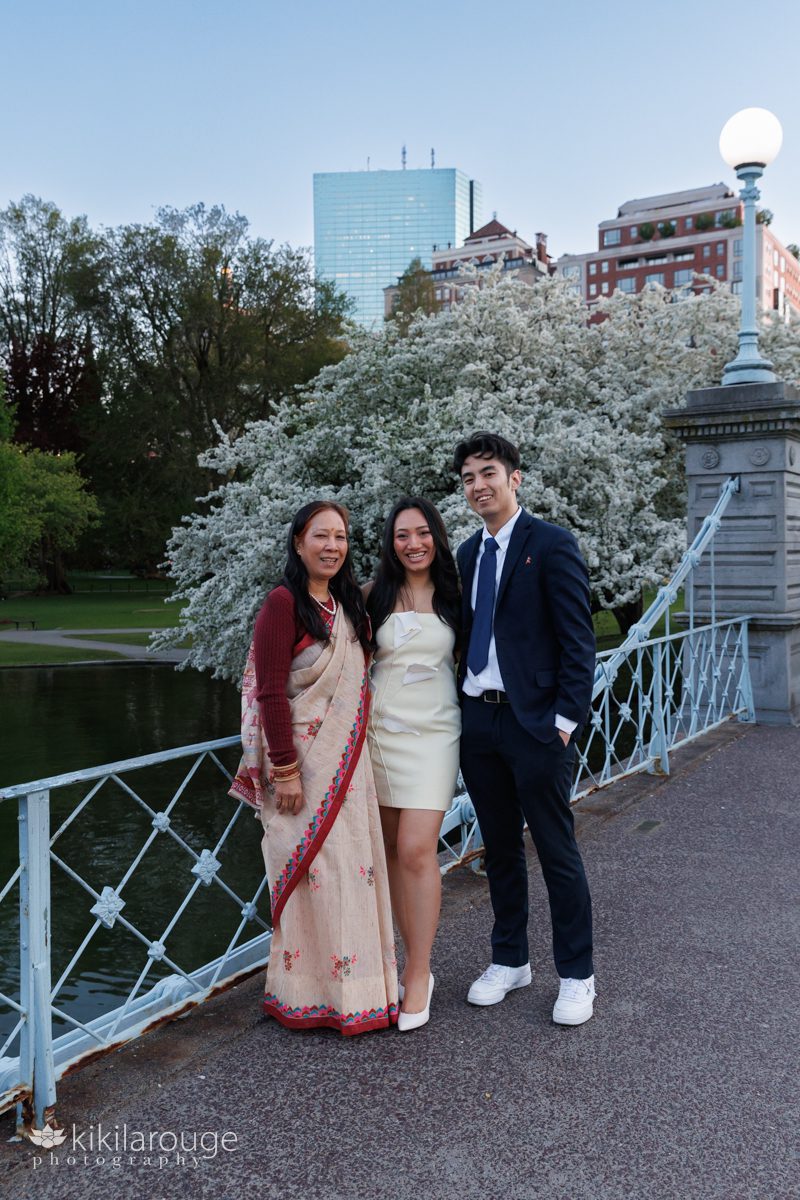 Woman in sari with her daughter and her boyfriend in Boston on the Public Garden bridge and the Prudential building and pond in the back drop