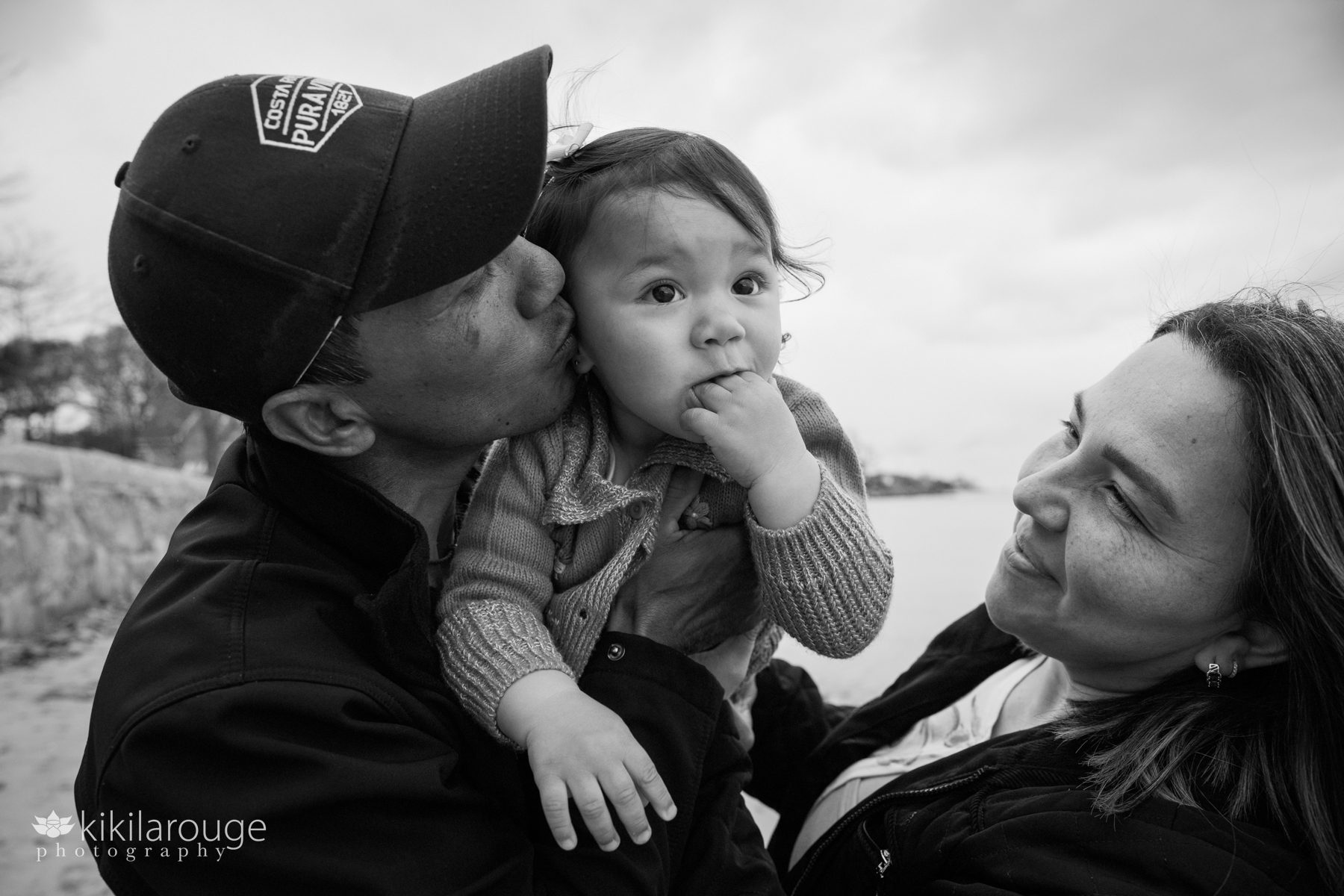 Couple holding and kissing their toddler daughter at the beach