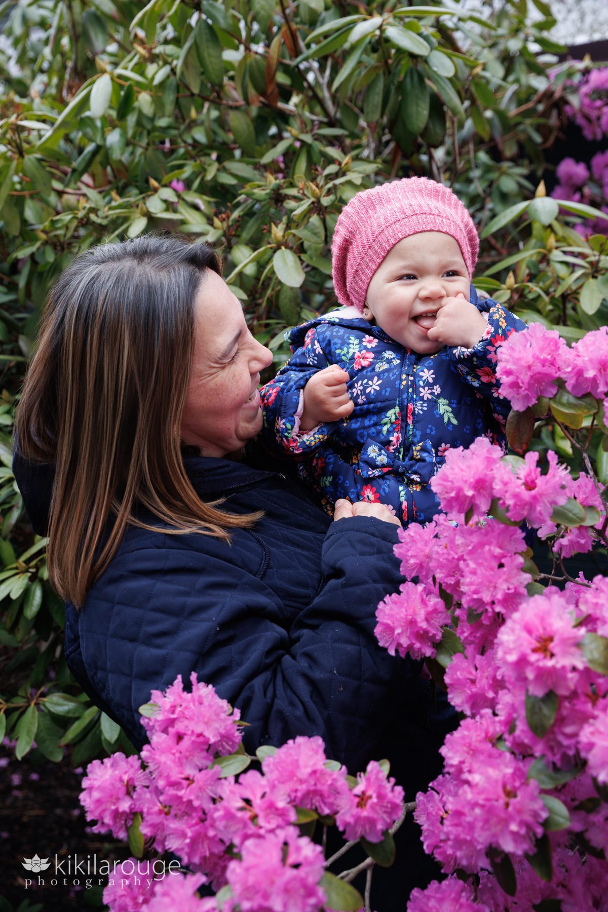 Mom and her daughter surrounded by flowers and leaves laughing together 