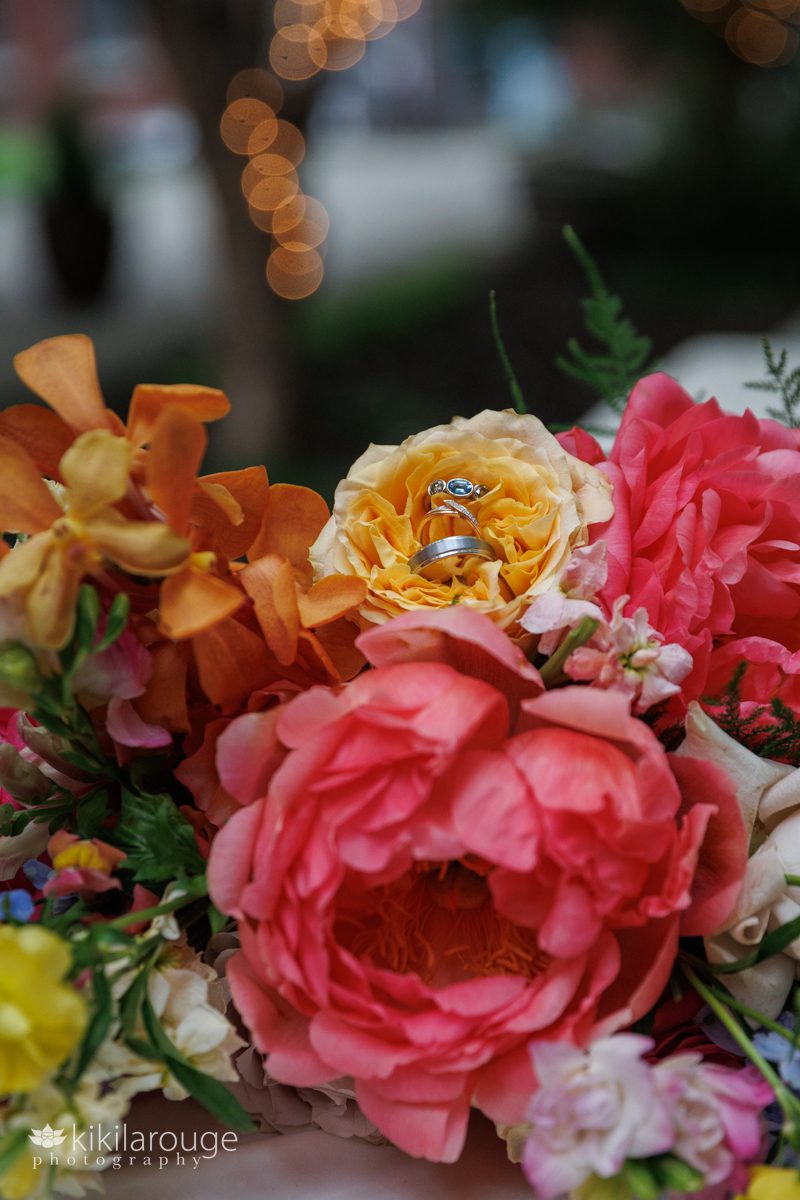 Bride's colorful wedding bouquet with wedding and engagement rings in the flowers 