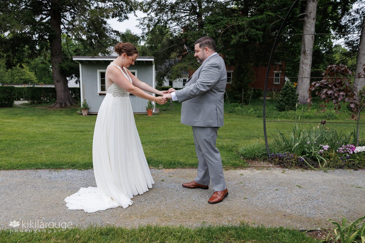 Groom seeing the bride for the first time in garden with gray shed in backdrop