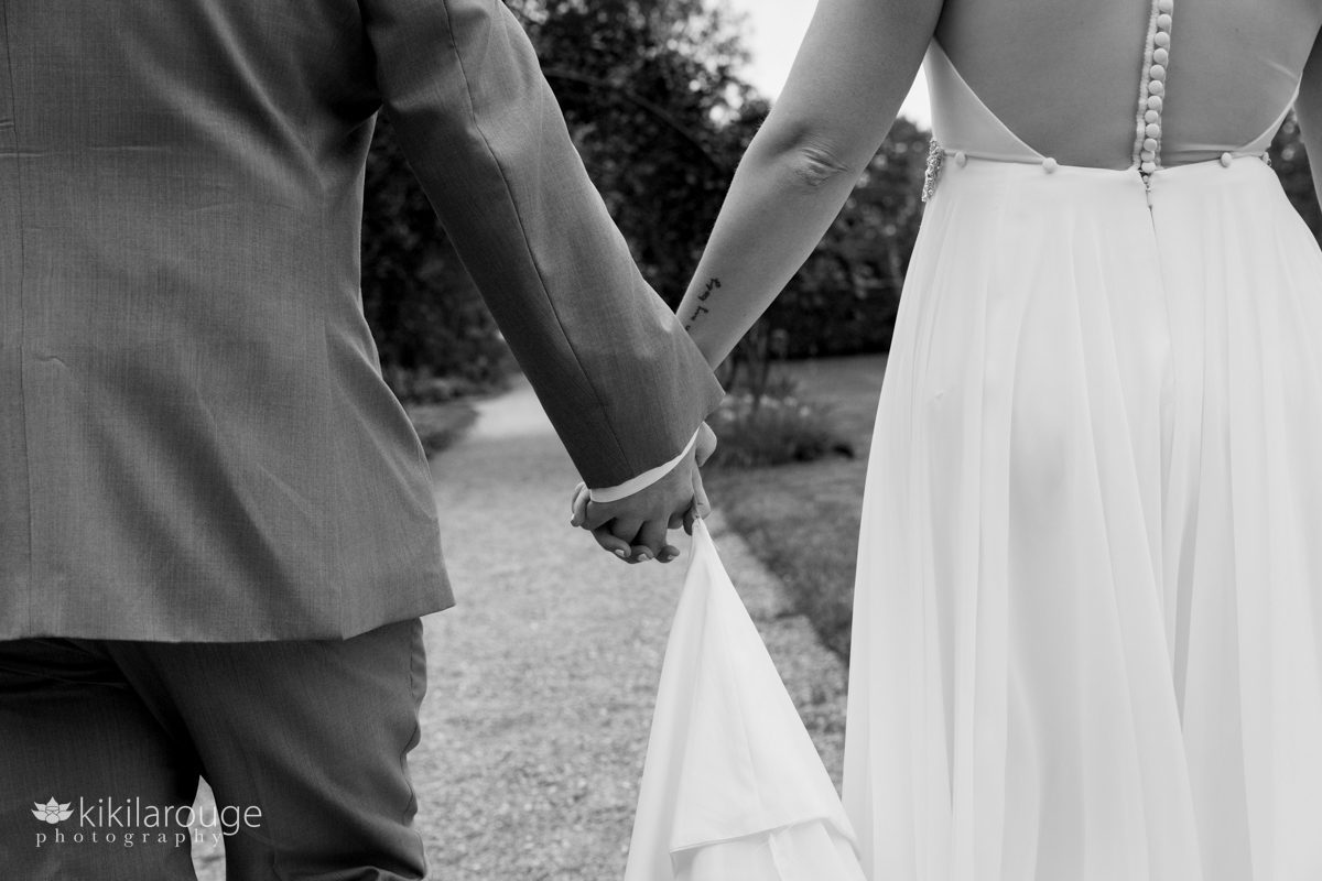 Close up of couple holding hands walking away down gravel path