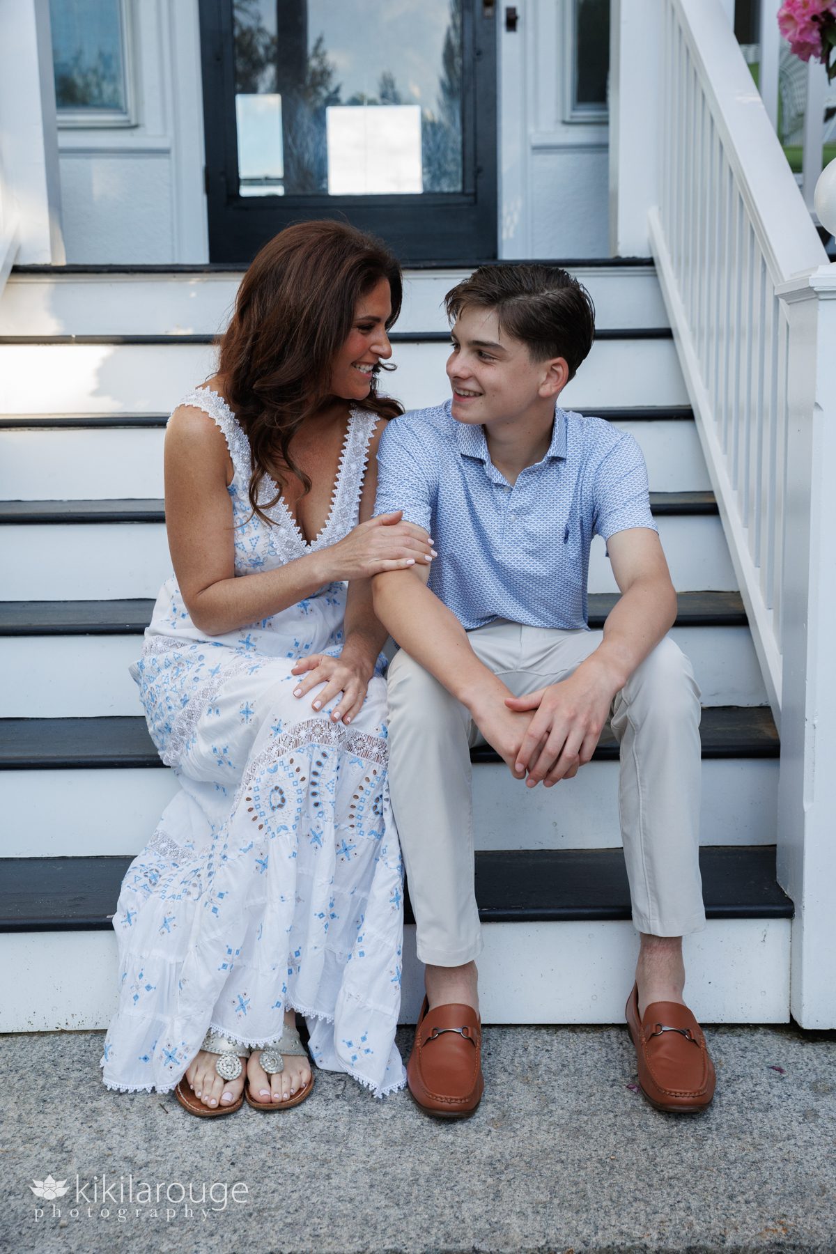 Mom and son sitting on white stops looking and smiling at each other