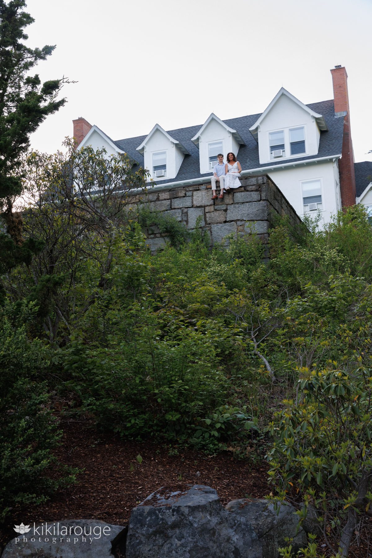 Mom and son sitting up on a high stone wall with White House in the background 