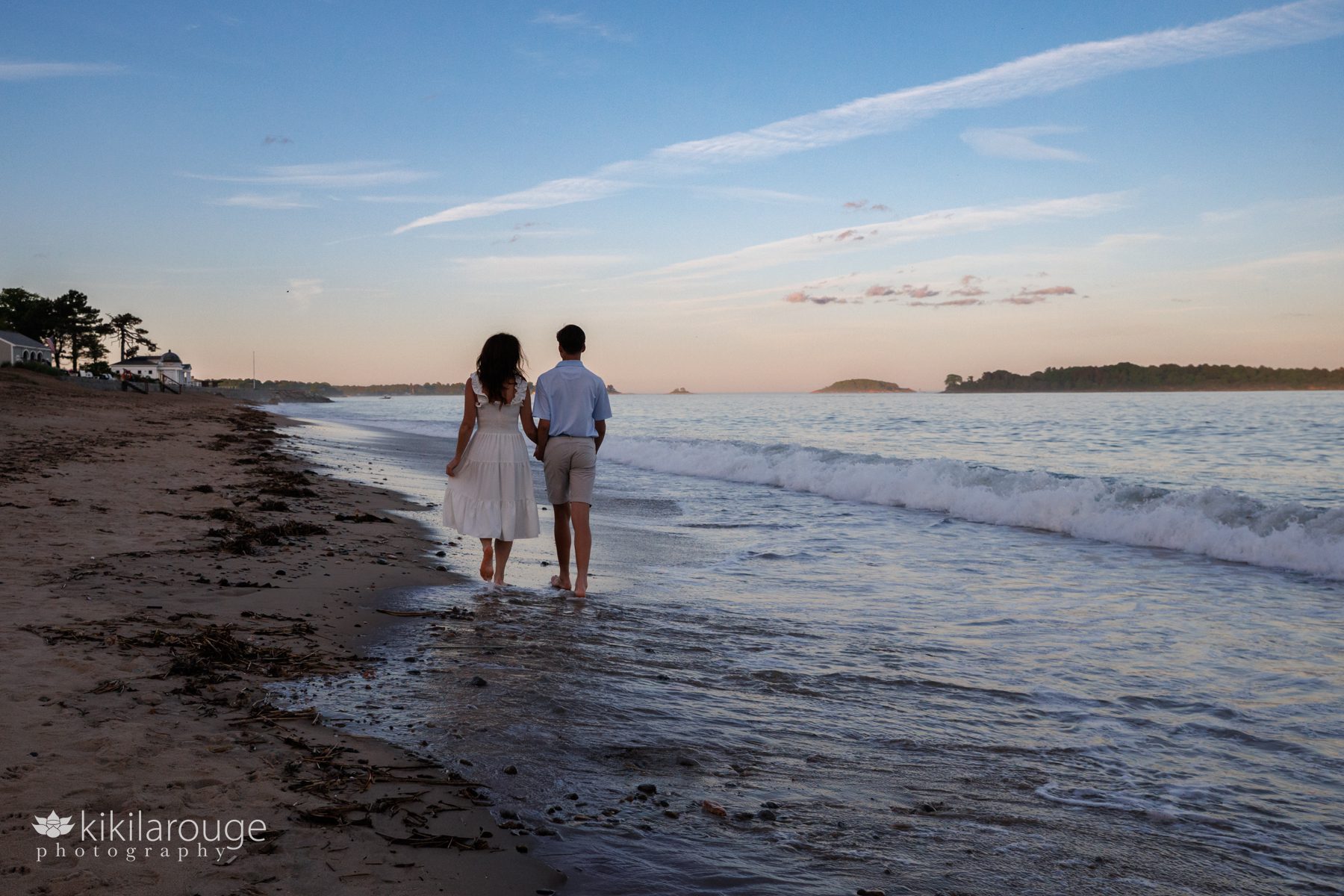 Mom and son walking down beach at sunset with waves crashing