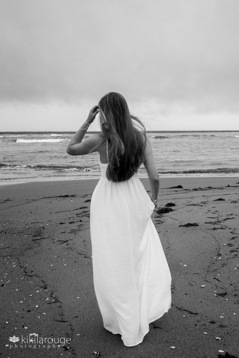BW of teen girl out of focus walking on beach towards the ocean