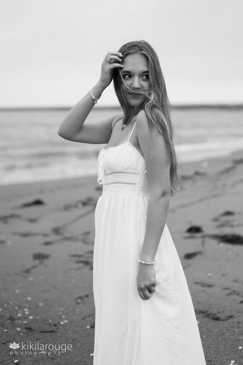BW of teen girl looking off to the side with wind blowing at beach