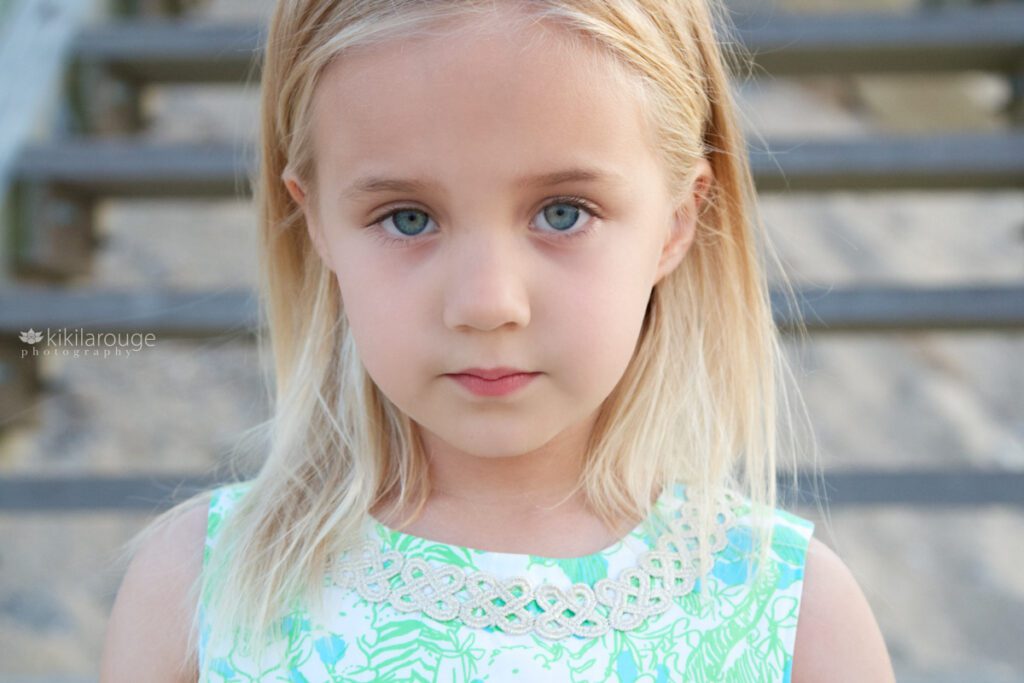 Young girl in green floral dress staring directly into the camera