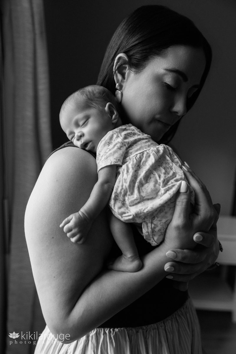 BW of a newborn sleeping on her Mom's shoulder in silhouette with Mom looking down